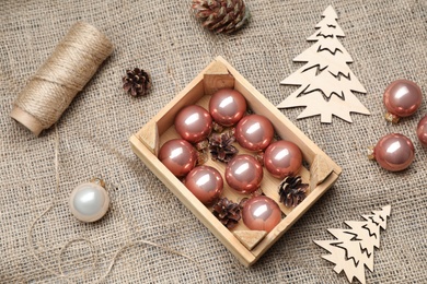 Composition with beautiful Christmas baubles and wooden crate on sacking, above view