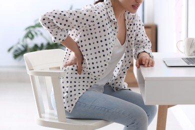 Photo of Woman suffering from back pain in office, closeup. Bad posture problem