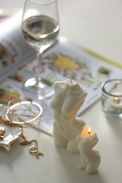 Beautiful body shaped candles and jewelry on white table indoors