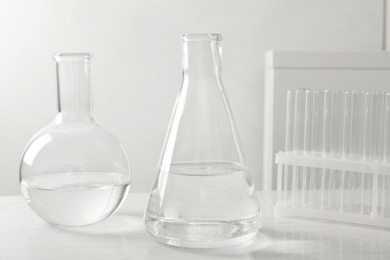 Laboratory glassware with transparent liquid on white wooden table