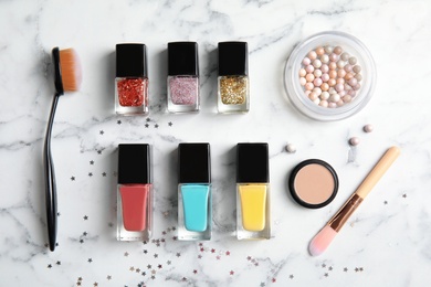 Flat lay composition with bottles of nail polish and different cosmetics on marble background