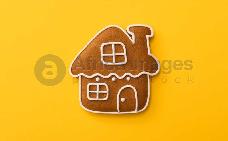 Christmas house shaped gingerbread cookie on yellow background, top view