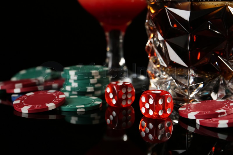 Casino chips, dice and alcohol drinks on dark background, closeup