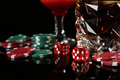 Casino chips, dice and alcohol drinks on dark background, closeup