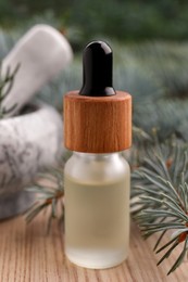 Pine essential oil and branches on white wooden table, closeup