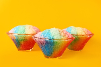 Rainbow shaving ice in glass dessert bowls on orange background