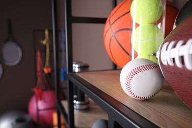 Different sport balls on shelf in room with other sports equipment