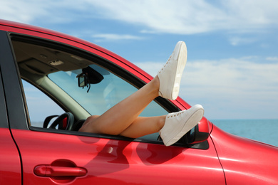 Woman showing legs from car, closeup. Summer vacation trip