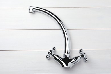 Double handle water tap on white wooden table, top view