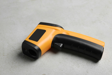 Modern non-contact infrared thermometer on light grey stone background