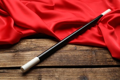 Beautiful black magic wand and red fabric on wooden table