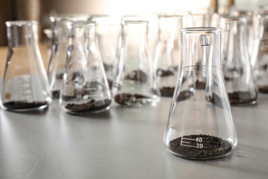 Glassware with soil samples on grey table. Laboratory research