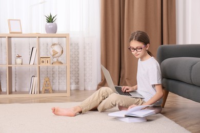 Girl with laptop and books sitting on floor at home