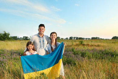 Family holding national flag of Ukraine in field. Space for text