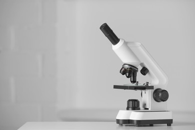 Modern microscope on table indoors. Space for text