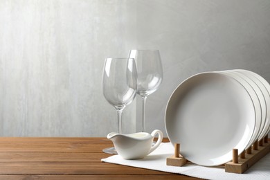 Set of clean dishware and glasses on wooden table, space for text