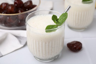 Photo of Glass of delicious date smoothie with mint on white table, closeup