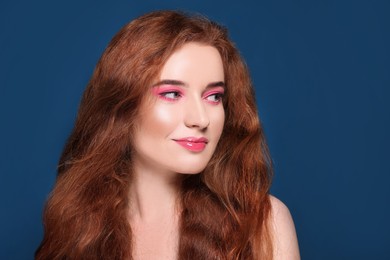 Photo of Portrait of beautiful young woman with makeup posing on blue background