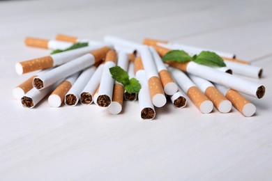 Menthol cigarettes and mint on white wooden table. Space for text