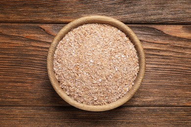 Bowl of wheat bran on wooden table, top view