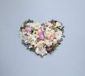 Beautiful heart made of different flowers on light gray background, top view