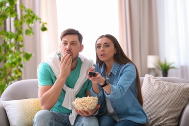 Couple watching movie with popcorn in living room