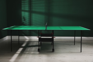 Green ping pong table with net in room