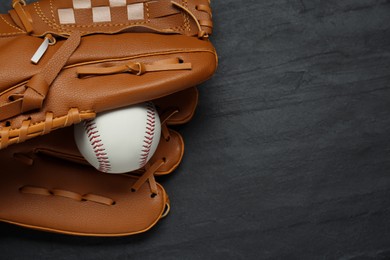Photo of Catcher's mitt and baseball ball on black slate background, top view with space for text. Sports game
