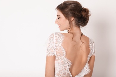Young bride wearing beautiful wedding dress on light background