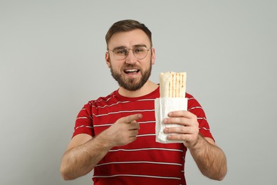 Photo of Young man with delicious shawarma on grey background