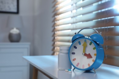 Alarm clock and pills on white table indoors, space for text. Insomnia treatment