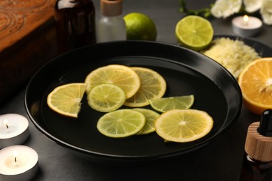 Photo of Bowl of essential oil and lemons on grey table. Aromatherapy treatment