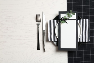 Stylish elegant table setting and blank card on wooden background, top view. Space for text