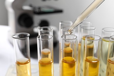 Dropping urine sample for analysis into tube in laboratory, closeup