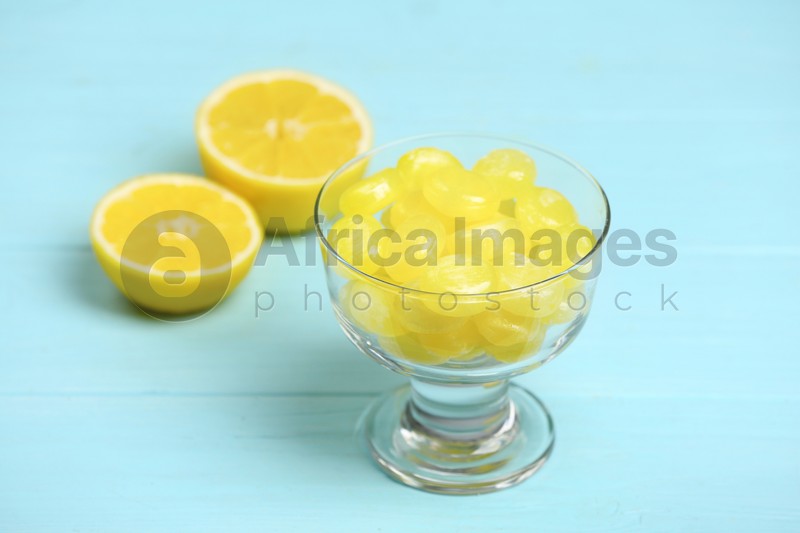 Tasty lemon drops in dessert bowl on light blue wooden table