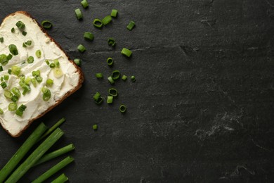 Photo of Delicious sandwich with cream cheese and chives on black table, flat lay. Space for text