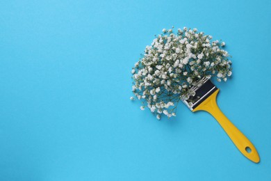 Creative composition with paint brush and gypsophila flowers on light blue background, top view. Space for text