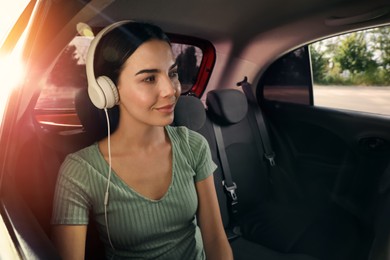 Photo of Young woman listening to music in modern taxi, space for text