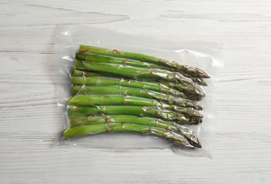 Asparagus in vacuum pack on white wooden table, top view