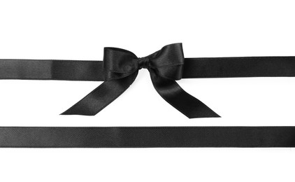 Black satin ribbons with bow on white background, top view