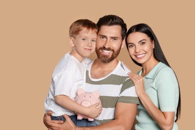 Happy family with ceramic piggy bank on beige background