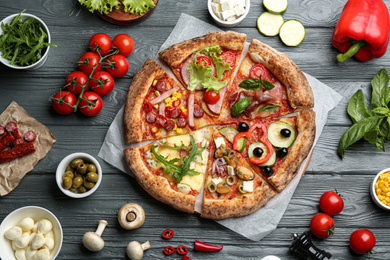 Flat lay composition with slices of different delicious pizzas on grey wooden table
