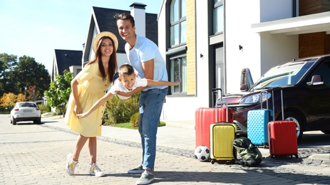 Happy family with suitcases near house outdoors. Moving day
