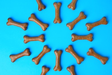 Photo of Bone shaped dog biscuits on light blue background, flat lay