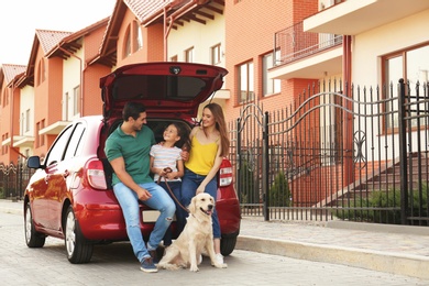 Happy family with dog near car on street