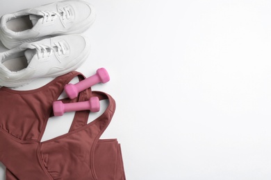 Sportswear and dumbbells on white background, flat lay with space for text. Gym workout