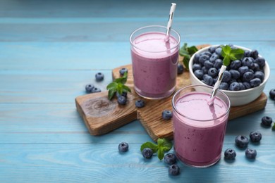 Photo of Glasses of blueberry smoothie with mint and fresh berries on turquoise wooden table. Space for text