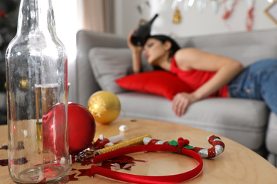 Young woman suffering from hangover  after New Year party, focus on messy table