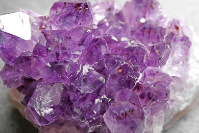Photo of Beautiful purple amethyst gemstone on grey table, closeup
