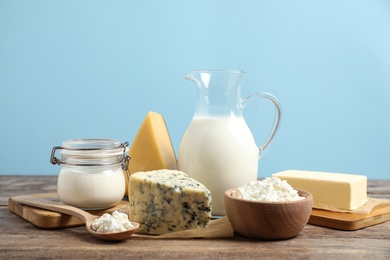 Photo of Different dairy products on wooden table against blue background